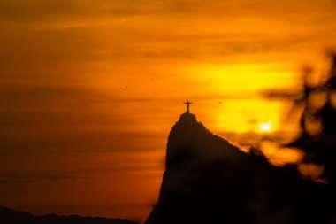Rio de Janeiro, Brezilya - CIRCA 2021: Cristo Redentor Panoraması (Kurtarıcı İsa) turuncu gökyüzü ile günbatımında