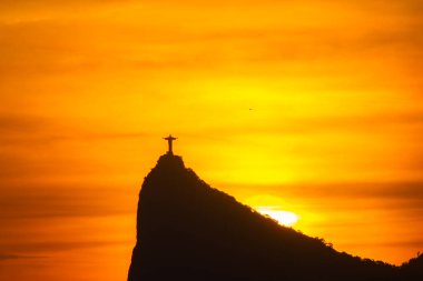 Rio de Janeiro, Brezilya - CIRCA 2021: Cristo Redentor Panoraması (Kurtarıcı İsa) turuncu gökyüzü ile günbatımında