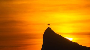 Rio de Janeiro, Brezilya - CIRCA 2021: Cristo Redentor Panoraması (Kurtarıcı İsa) turuncu gökyüzü ile günbatımında