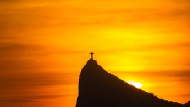 Rio de Janeiro, Brezilya - CIRCA 2021: Cristo Redentor Panoraması (Kurtarıcı İsa) turuncu gökyüzü ile günbatımında