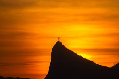 Rio de Janeiro, Brezilya - CIRCA 2021: Cristo Redentor Panoraması (Kurtarıcı İsa) turuncu gökyüzü ile günbatımında