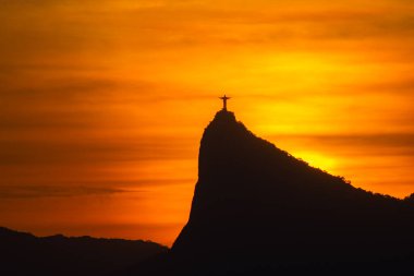 Rio de Janeiro, Brezilya - CIRCA 2021: Cristo Redentor Panoraması (Kurtarıcı İsa) turuncu gökyüzü ile günbatımında