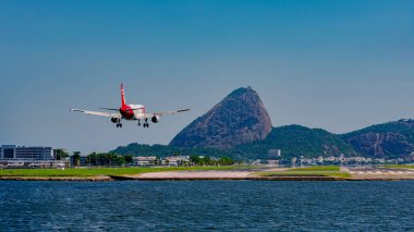 Rio de Janeiro, Brezilya - CIRCA 2020: Santos Dumont ulusal havaalanına ticari uçak iniyor. Rio 'nun turistik merkezi Guanabara Körfezi ve Sugarloaf Dağı' nı görmek mümkün.