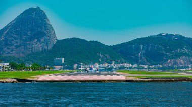 Rio de Janeiro, Brezilya - CIRCA 2020: Santos Dumont ulusal havaalanına ticari uçak iniyor. Rio 'nun turistik merkezi Guanabara Körfezi ve Sugarloaf Dağı' nı görmek mümkün.