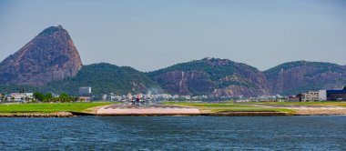 Rio de Janeiro, Brezilya - CIRCA 2020: Santos Dumont ulusal havaalanına ticari uçak iniyor. Rio 'nun turistik merkezi Guanabara Körfezi ve Sugarloaf Dağı' nı görmek mümkün.