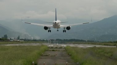 Büyük bir uçak dağlarda bir şeride iniyor.