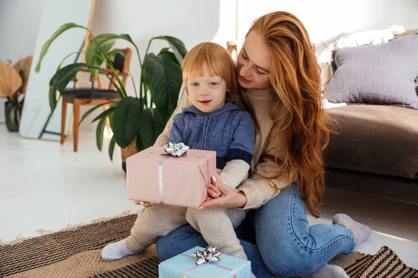 Mãe de cabelos vermelhos alegremente prepara presentes de Natal com seu filho — Fotografia de Stock