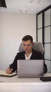 Odaklanmış bir öğrenci çevrimiçi ders dinler ve not defterine notlar alır.