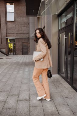 Uzun boylu, dizüstü bilgisayarı olan modern kız tasarımcı ofiste çalışıyor.