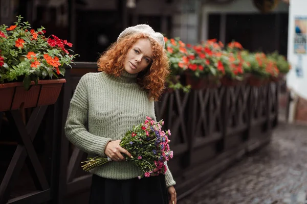 Γυναίκα πορτρέτο σε ένα μπερέ πουλόβερ κρατώντας ένα μπουκέτο λουλούδια του εστιατορίου φόντο — Φωτογραφία Αρχείου
