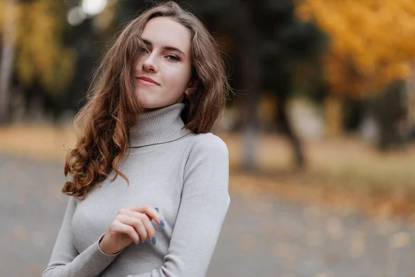 Retrato de niña sonriente con un vestido gris en el parque de otoño —  Fotos de Stock
