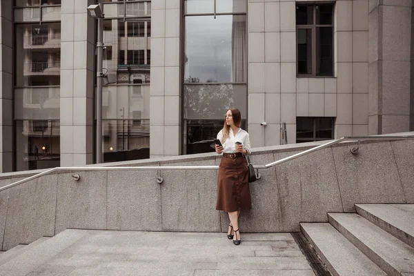  Modern ofis geçmişinin telefonunu tutan genç bir iş kadını. 