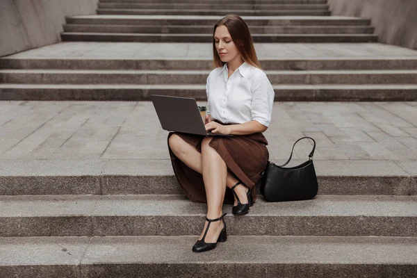 사업을 하는 젊은 여성 이현대 사무실 건물의 노트북 컴퓨터를 가지고 계단에 앉아 있는 모습 — 스톡 사진