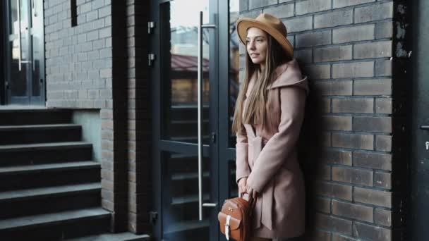 Πορτραίτο της νεαρής γυναίκας σε παλτό και καπέλο του κτιρίου του γραφείου φόντο — Αρχείο Βίντεο