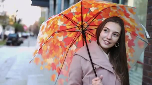 Чарівна молода довгошерста жінка під парасолькою, що йде вулицею мегаполісу — стокове відео