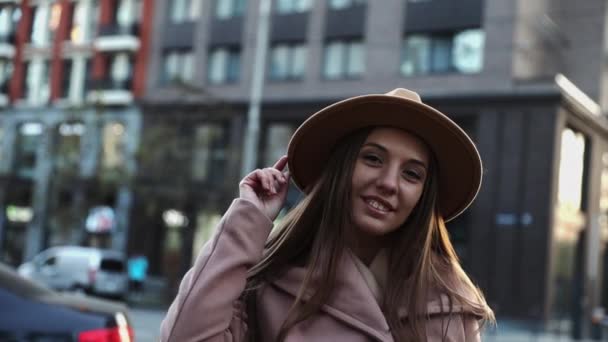 Portrét pěkně dlouhých vlasů mladé ženy v kabátě a kulatém klobouku ve městě — Stock video
