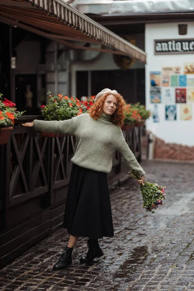 Retrato de mujer en un suéter de boina sosteniendo un ramo de flores y caminando — Foto de Stock