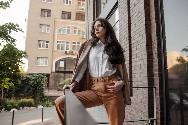 Menina elegante alto com casaco de grandes dimensões posando perto do corrimão e passos no fundo da cidade — Fotografia de Stock