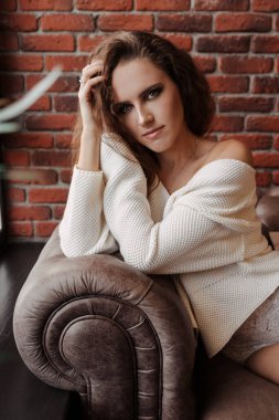 Beyaz pijamalı güzel kıvırcık kız kanepede yatıyor.