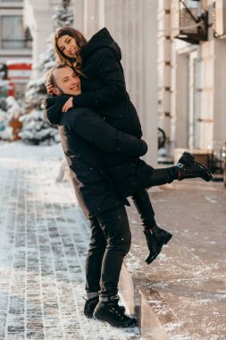 A loving couple in red sweater hugs of a red bus background. Valentines Day concept