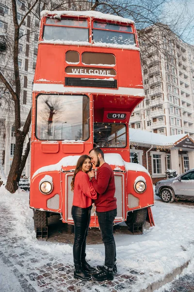 Una pareja amorosa en suéter rojo abraza un fondo rojo autobús. Concepto de San Valentín — Foto de Stock