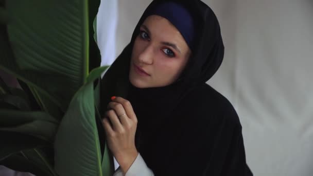 Hermosa mujer musulmana en abaya árabe tradicional vestido con planta verde — Vídeo de stock