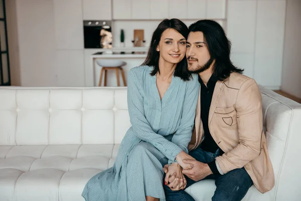 Супружеская пара сидит на роскошном белом диване в своей новой квартире — стоковое фото