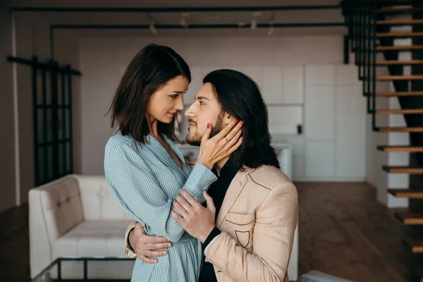 Ung man kramar försiktigt sin fru i vardagsrummet — Stockfoto