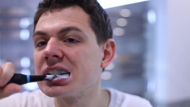 Mann putzt seine Zähne mit einer elektrischen Zahnbürste. Zahnaufhellung, Zahnpflege — Stockvideo