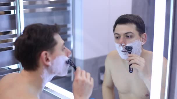 Hezký muž holení jeho vousy v koupelně mechanickou holicí strojek — Stock video