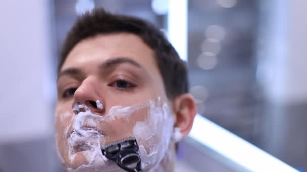 Hombre guapo afeitándose la barba en el baño por maquinilla de afeitar — Vídeos de Stock