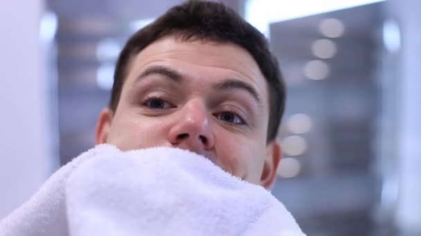 Hezký muž pohled v zrcadle v koupelně třít tvář s ručníkem po sprše — Stock video