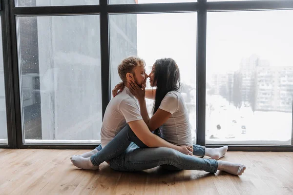 Pasangan dalam pelukan cinta yang lembut dalam lingkungan rumah yang nyaman dan jendela panorama — Stok Foto