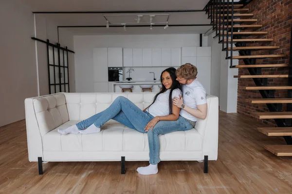 Un couple marié est assis sur un canapé blanc luxueux dans leur nouvel appartement — Photo