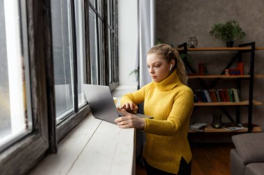 Genç bir kadın evdeki dizüstü bilgisayarında video görüşmesi yapıyor.