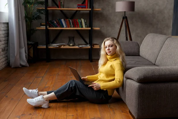 집 바닥에 앉아서 랩탑으로 일하는 젊은 여자. — 스톡 사진