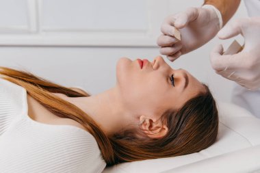 Doktor burun ameliyatından sonra hastayı muayene ediyor.