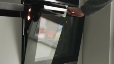 Bir kadın eli fırının kapısını açar ve fırında patatesle bir deco çıkarır.