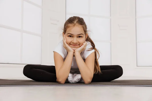 Jovem menina alegre fazendo exercícios no tapete de fitness olhar para a câmera e sorrir — Fotografia de Stock