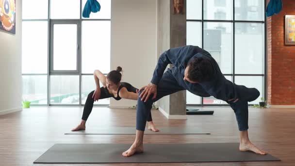 Homme et femme pratiquent l'exercice d'étirement synchrone en studio de yoga — Video