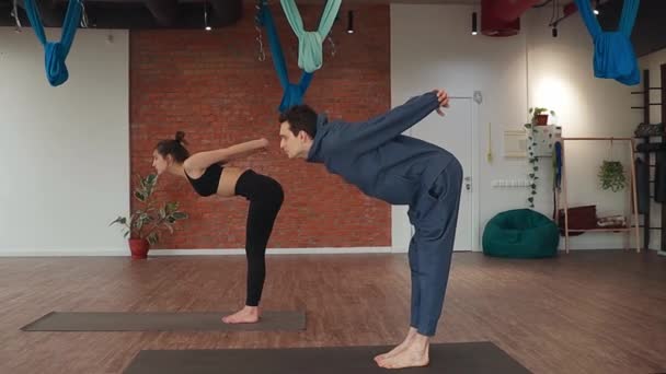 Man and woman doing synchronously tilt exercise on floor mat in yoga studio — Stock Video