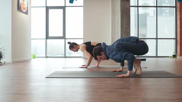 Hombre y mujer haciendo ejercicio de mano sincrónica en alfombra de piso en estudio de yoga — Vídeos de Stock