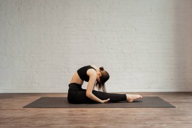  Genç bir kadın spor egzersizi yapıyor. Forward Bend 'de oturuyor. Paschimottanasana