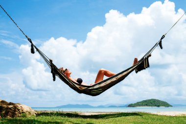 Yaz tatili konsepti. Siyah bikinili mutlu kadın tropik plajda hamakta dinleniyor.