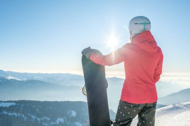 Snowboard yapan ve dağ manzarasının tadını çıkaran kadın snowboardcu.