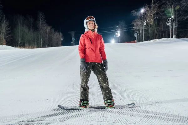 Mujer con snowboard en la pista de esquí. Evening riding Fotos De Stock