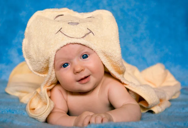 Glimlachende baby liggend op een blauwe achtergrond — Stockfoto
