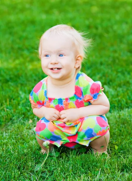 Søt, morsom, liten jente som sitter på gress – stockfoto