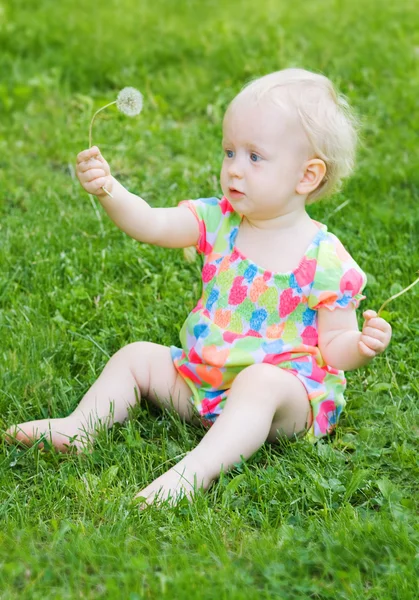 Bonito engraçado bebê menina sentado na grama com flores — Fotografia de Stock