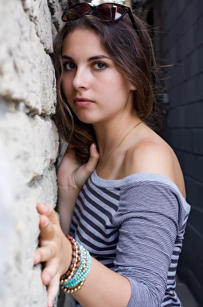 Chica en camisa a rayas por pared de piedra — Foto de Stock